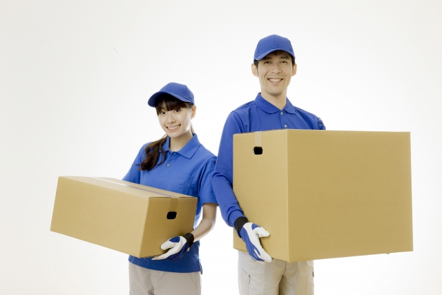 引っ越し屋の男女が荷物を持っている