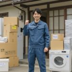 引っ越し屋の社長が荷物の前でポーズしている