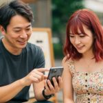 男性が女性にスマホの操作を教えている